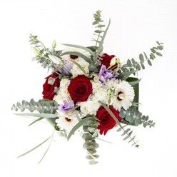 As a seasoned Uxbridge florist, I see this bouquet as an embodiment of quiet strength and cohesive artistry, familiar to those strolling along Uxbridge High Street. The white gerberas, with their creamy halos and dark, inviting centers, anchor the display while the elegantly spiraled red roses add a passionate note-perfect for commemorating lasting bonds or tender sympathy. Eucalyptus sprigs stretch upwards, their silver-tinged leaves catching the light like dewdrops after rain along Rockingham Recreation Ground. Delicate lilac lisianthus, scattered in both buds and blossoms, bring contemporary flair reminiscent of gentle breezes on summer evenings in Uxbridge. Cloud-like white filler flowers soften the lines, and lush, broad foliage wraps neatly around the base, framing the ensemble in rich greenery. Each stem sits submerged in crystal-clear water within a glass vase, preserving the flowers' vitality and reinforcing the bouquet's sense of renewal. Whether celebrating milestones or simply expressing gratitude, this locally arranged display reflects the dedication and artistry cultivated within the heart of Uxbridge.